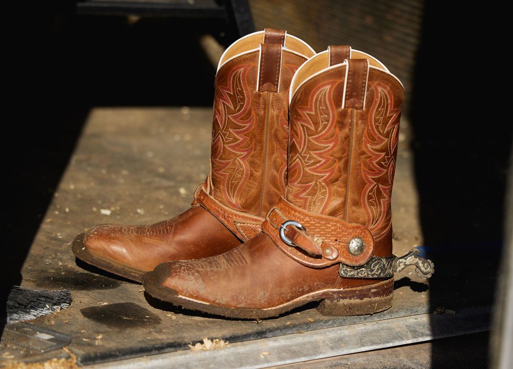 A close up photo of cowboy boots placed in a barn.